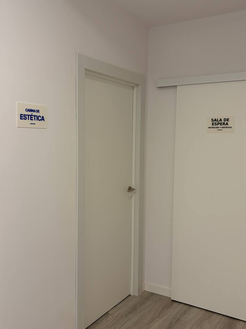 Rótulos de CABINA DE ESTÉTICA y SALA DE ESPERA en el pasillo de un gabinete