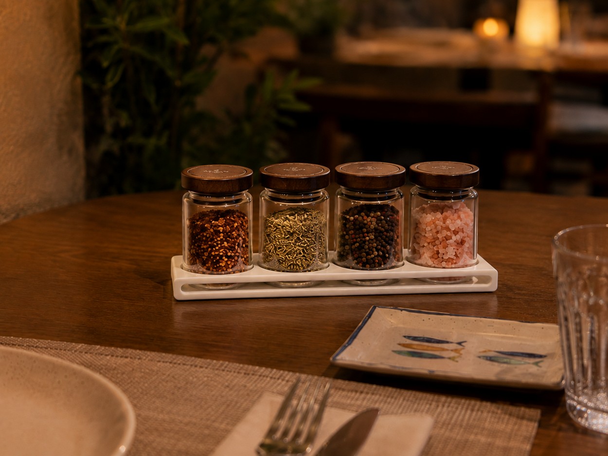 Especiero de mesa impreso en 3D con cuatro botes de especias sobre una mesa de restaurante