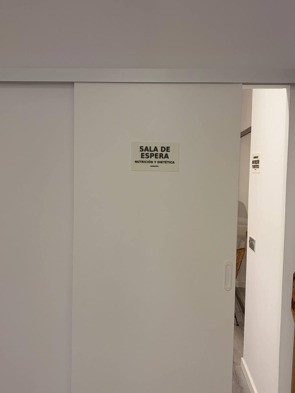 Rótulo SALA DE ESPERA NUTRICIÓN Y DIETÉTICA sobre una puerta corredera blanca